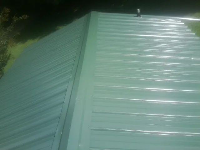 New green metal panels meeting at the ridge of a roof — Flat Roof Repair work by our crew in Nemaha