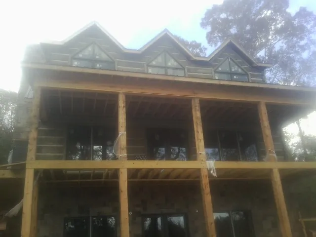 Dormers and porch framing on a large log home under construction — Roof Coating work by our crew in Nemaha