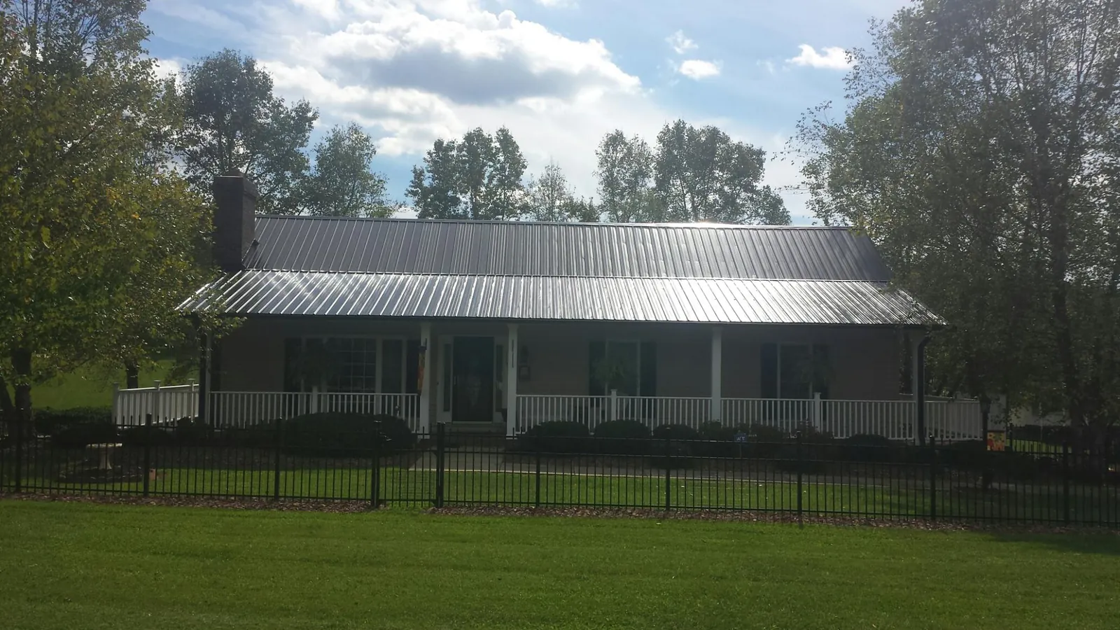 Gray metal roof on a brick ranch with a full width front porch — Gutter Guard Installation work by our crew in Nemaha
