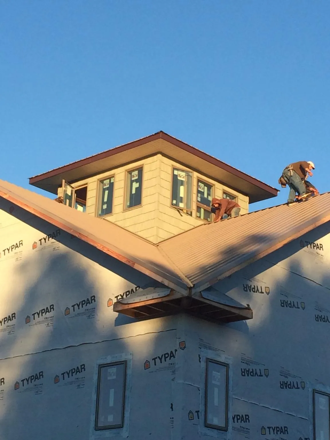 Roofers working around a rooftop cupola on a new metal roof at sunset — Roof Waterproofing in Nemaha by Roofing Brothers